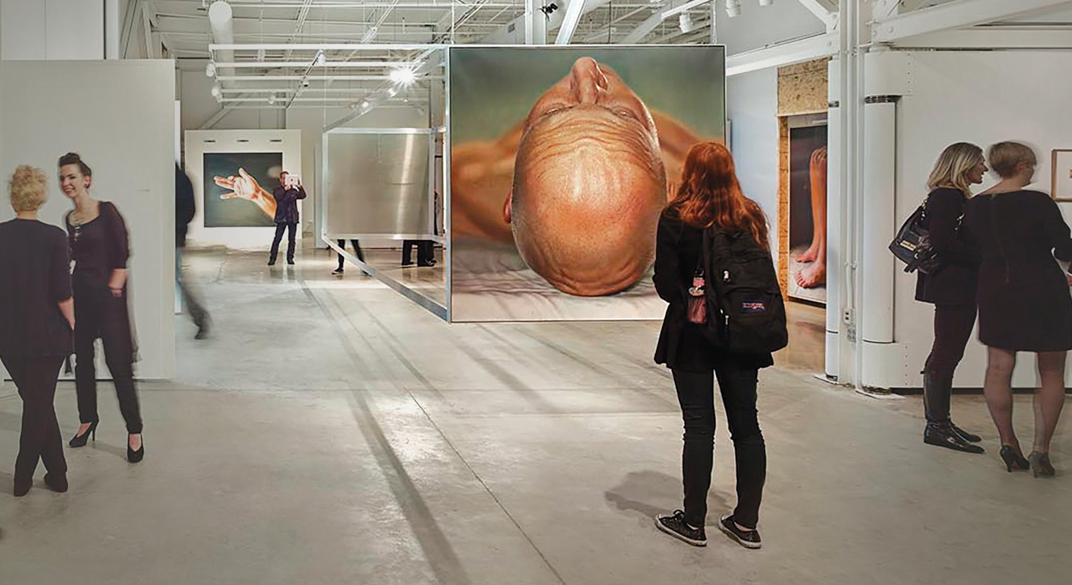 a woman examines a painting in an industrial museum setting